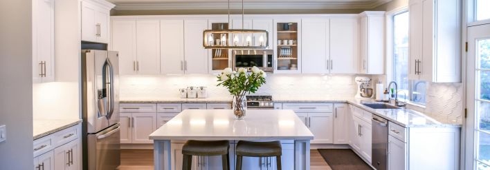 Spacious and elegant kitchen featuring white cabinetry, island, and stainless steel appliances.