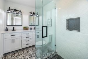 Elegant white bathroom with glass shower and stylish patterned floor.