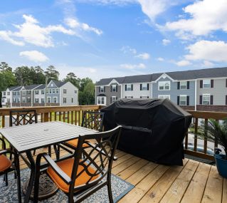 Charming wooden deck with furniture, grill, and suburban view.