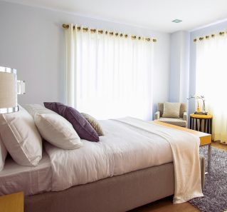Bright modern bedroom with sunlight, cozy decor, and soft furnishings.